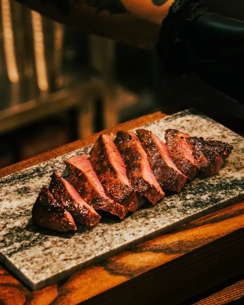Sliced flat iron steak resting on a stone board